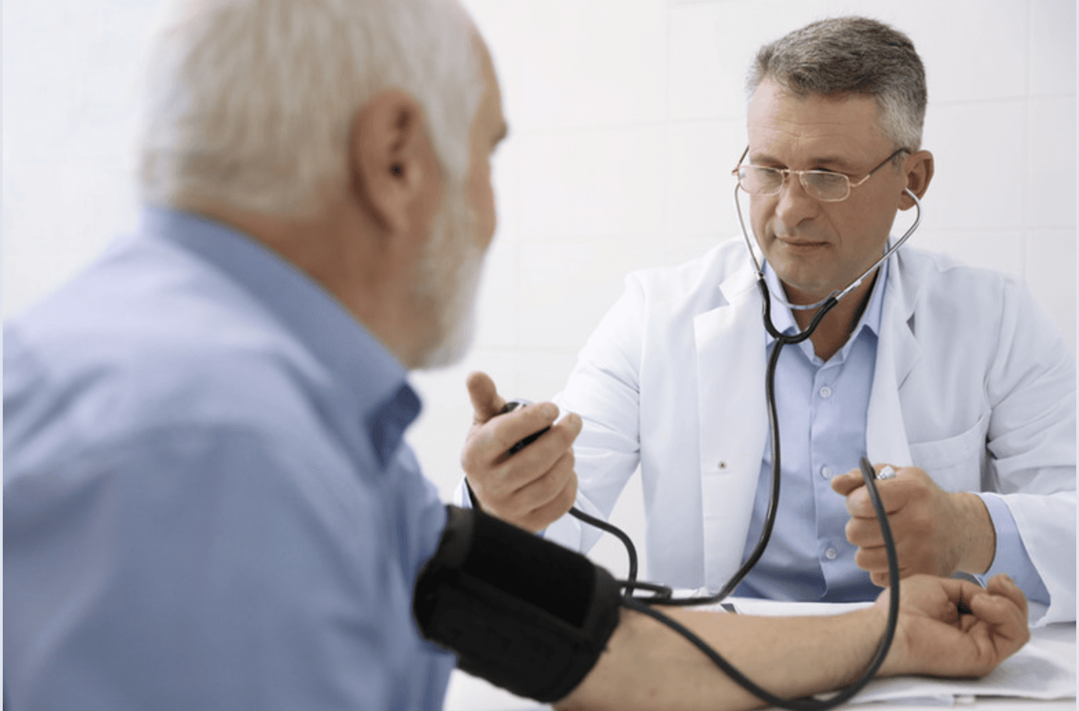 Médico controlando la presión arterial de un paciente en consulta